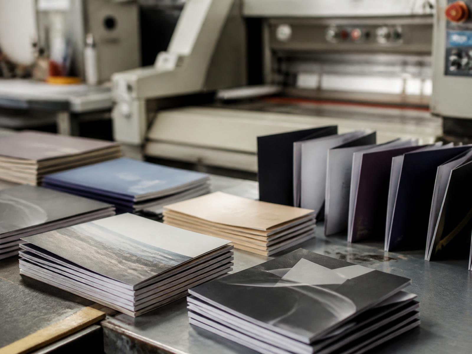 Freshly printed booklets and brochures stacked on a print finishing bench